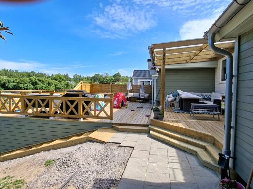 Altanbygge med nedsänkt SPA bad Trädgård med terrass, utemöbler och lekplats i soligt väder.
