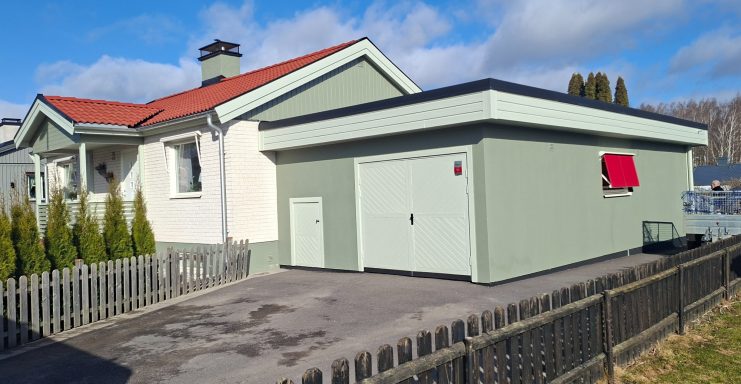 Hus målning En vit villa med röd takpannor och en grön garagebyggnad. Gräsmatta och staket i förgrunden.
